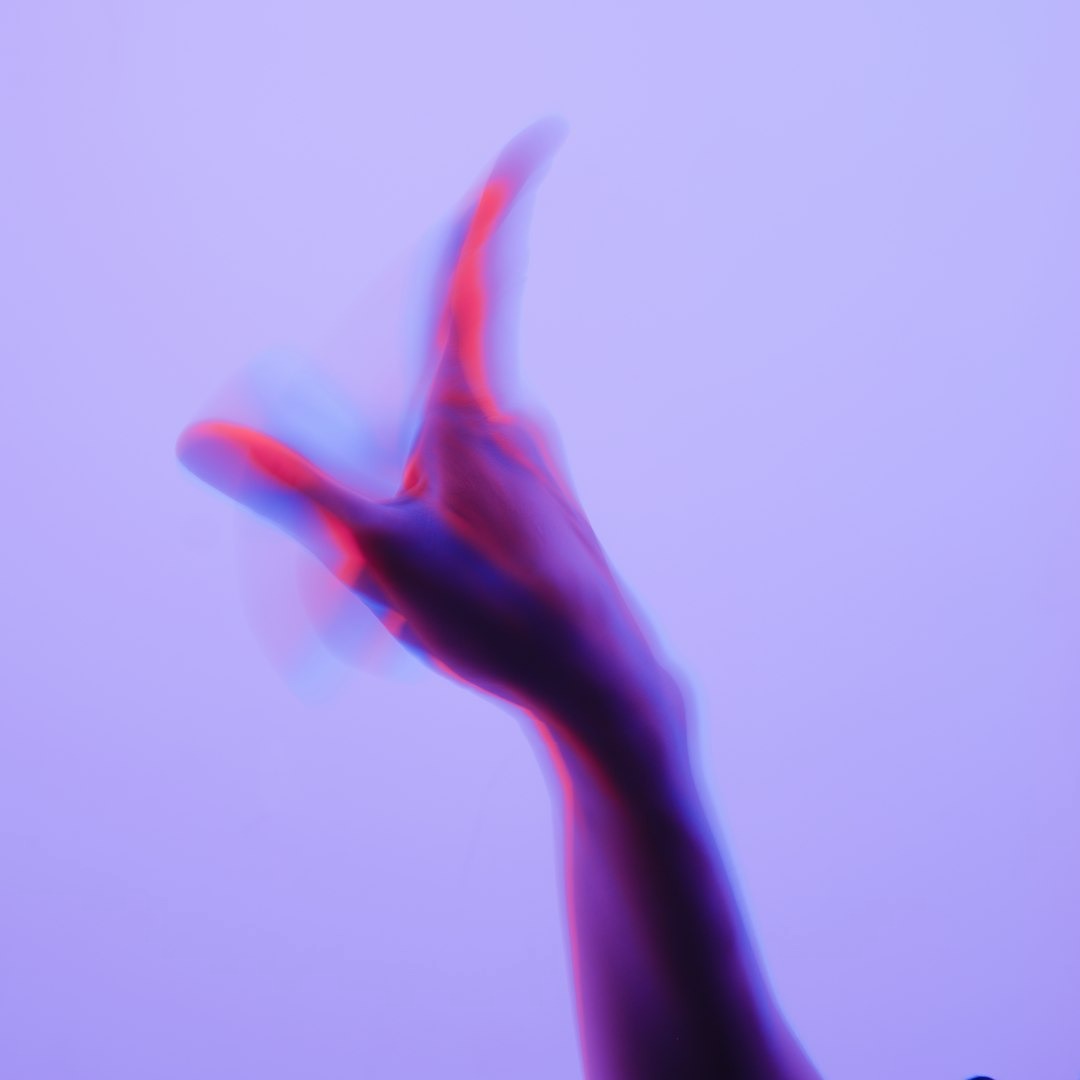 Human hand reaching up with a red and blue glitch effect.
